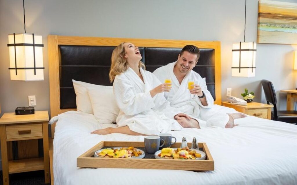 a couple enjoys breakfast in bed at the brentwood bay resort and spa, victoria bc