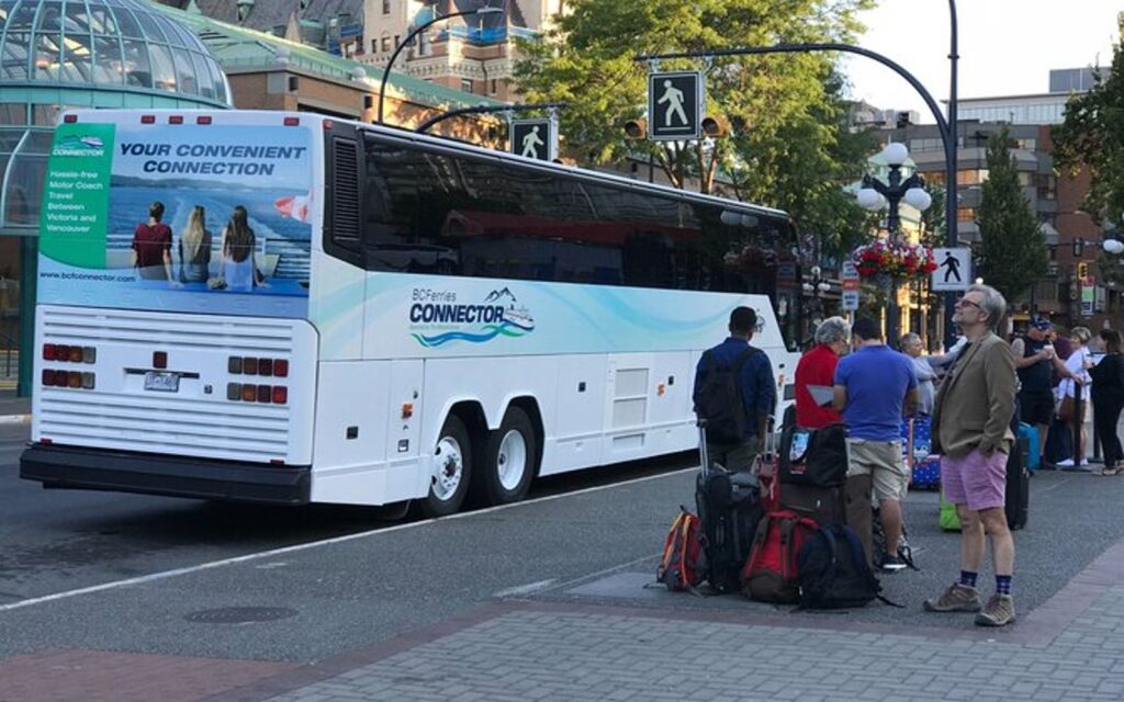 a group of travellers lines up to board the victoria to yvr bus