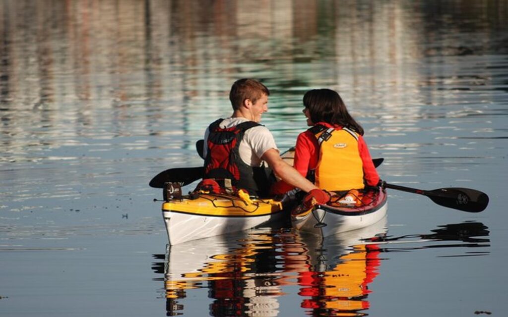 a couple on a victoria kayak tour paddles through the city's inner harbour