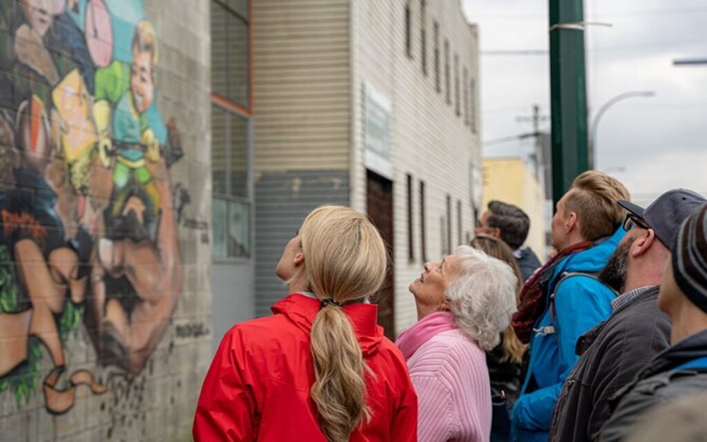 a group of participants on the victoria street art and brewery tour admires a local wall mural