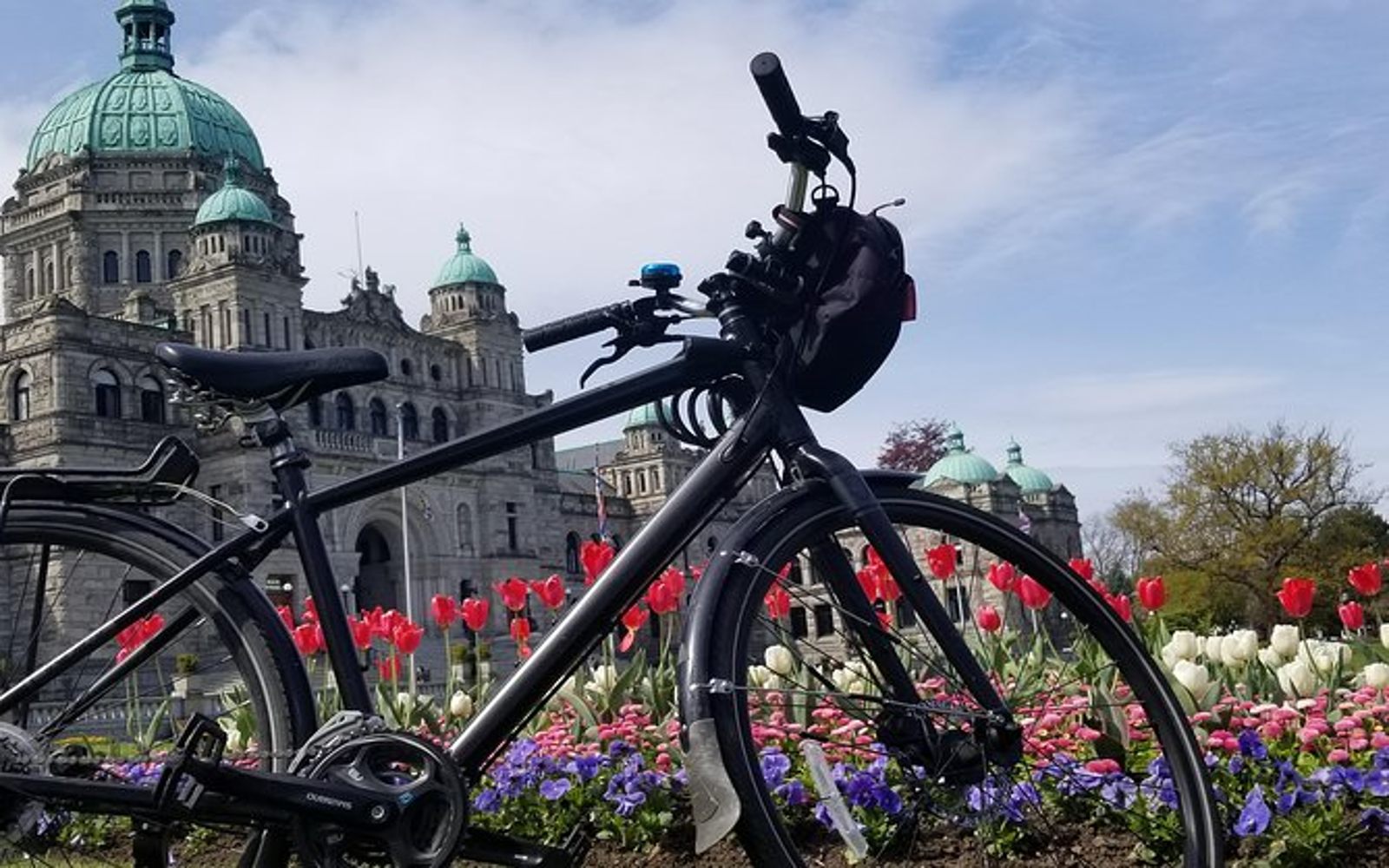 a bike sits in front of the Parliament Buildings on a Victoria bike tour.