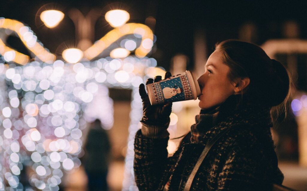 A woman sips a hot drink at a victoria bc christmas market.