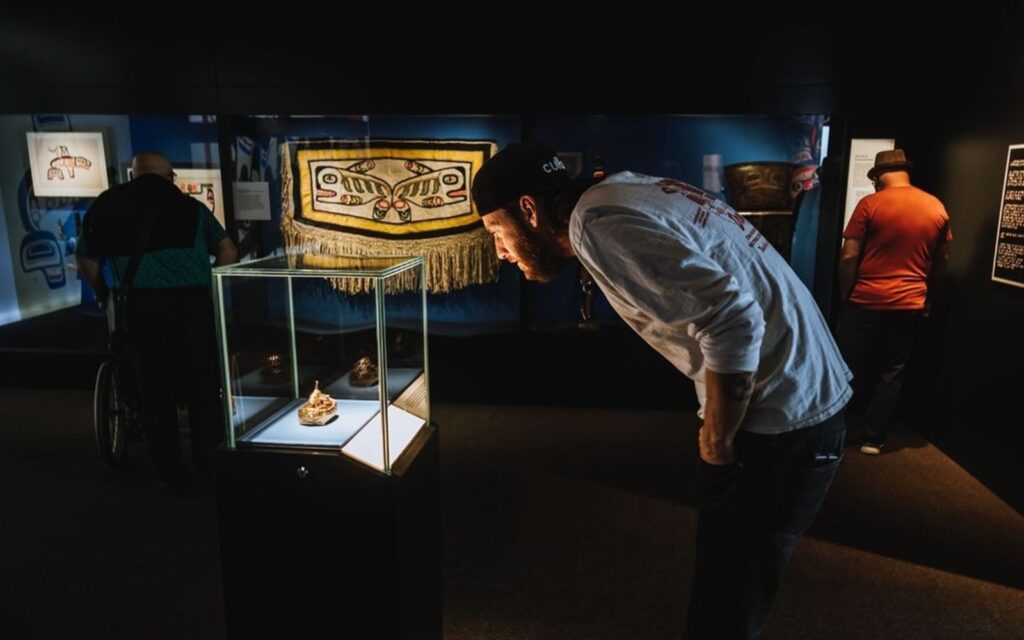 A man admires some indigenous artifacts at a museum.