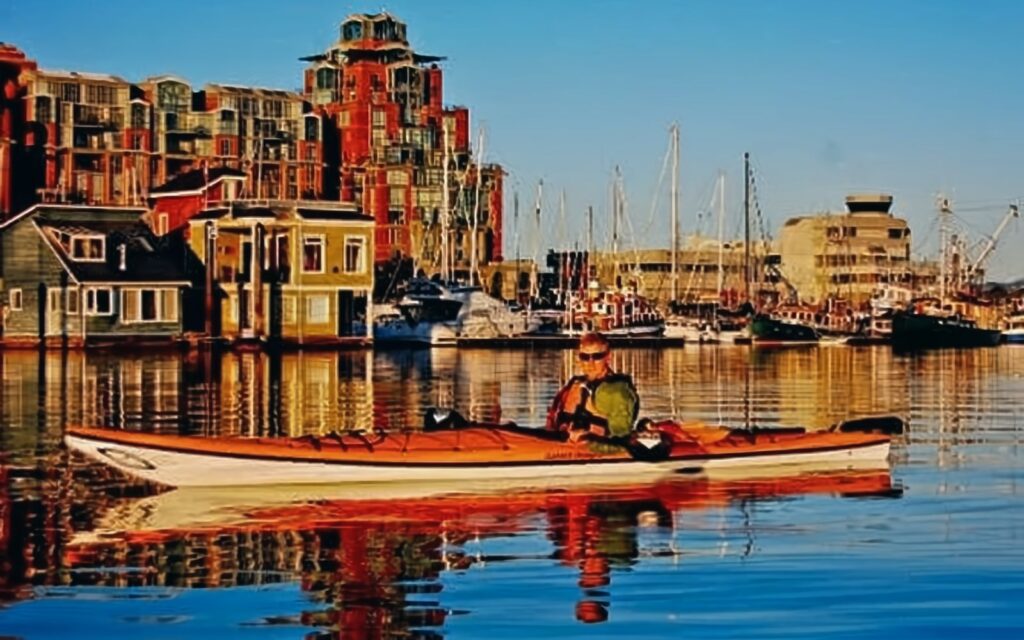 a man embarks on a Victoria kayaking tour in the Inner Harbour at dusk.